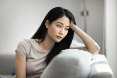 Kapalı, üzgün Asyalı kadın hayal kırıklığı yaşıyor, üzgün düşünceler içinde kaybolmuş ya da düşüncelere dalmış evde tek başına oturuyor, melankoli, yorgunluk ya da derin bir yansıma yayıyor. Kişisel endişeler, boşanma, ayrılık