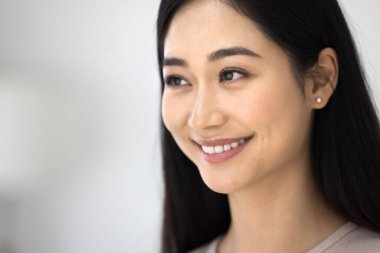 Yakından bakınca, güzel Asyalı bir kadın sıcak, güzel bir gülümsemeyle, alımlı bir görünüme sahip, pürüzsüz, temiz bir cilde sahip, makyajsız bir yüze sahip, arka planda bir kopyaya sahip. Doğal güzellik, kozmetoloji