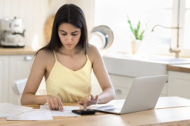 Finansal evraklar. Meşgul genç bir kadın ev işlerinde yurt içi finansmanı yönetir. Para için harcamaları hesaplar. Ekonomik kontrol ödemeleri faturalar, faturalar.