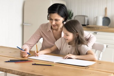 Büyükanneyle komik bir çizim. Gülümseyen olgun büyükanne, küçük kız torununa albüm desteğinde renkli eskizler çizmesinde yardımcı oluyor. Sanatsal hayal gücünde yeteneğin gelişmesinde, renkli kalemlerin nasıl kullanılacağını öğretiyor.