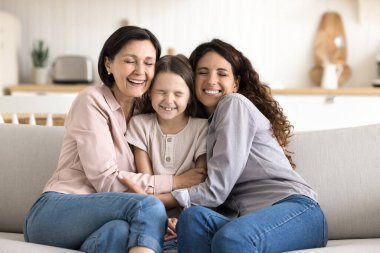 Gelmiş geçmiş en sıkı kucaklaşma. Mutlu, çoklu nesil aile portresi. Yaşlı, yaşlı, anne, küçük kız, torun. Rahat koltukta sarılıp, gözleri kapalı, oturma odasında eğlenirken.