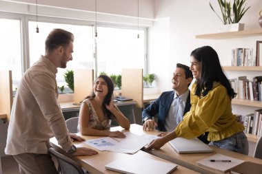 Çok kültürlü işbirliği ve iş eğlencesi. Neşeli kahkahalar atan çoklu etnik çeşitliliğe sahip gençler girişimci takımı bilim adamları evrak işleriyle uğraşan öğrenciler yaratıcı çalışma alanındaki veri istatistiklerini tartışıyor.