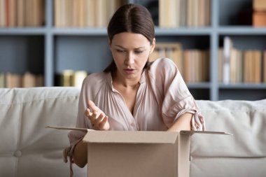 Kucak kutusuna konmuş koltukta oturan kadın hayal kırıklığına uğramış paketin bozuk ya da karışık mallar, olumsuz geri bildirim, yanlış sipariş, kötü ürün kalitesi, iade konsepti geldiğini hissediyor.