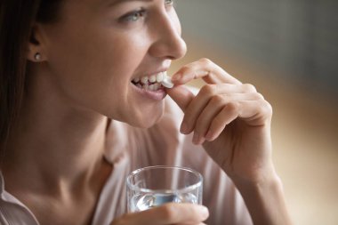 Yüzü kapalı gülümseyen 35 'lik genç bir kadın, elinde cam bardak, suda çözünen vitamin hapı, milenyum kadınlarının reçeteli ilaç içmesi, gıda takviyesi, sağlık konsepti...