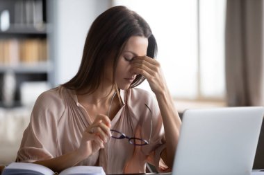 Evde oturma odasındaki ya da modern işyerindeki masada oturan kadın uzun süre laptopta çalıştıktan sonra gözlüklerini çıkartıyor. Göz yorgunluğu, masaj köprüsü burnu, acı veren duyguları azaltıyor.