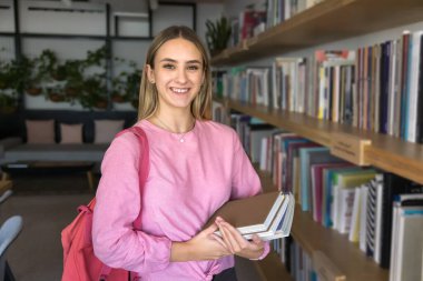 Genç kadın portresi, üniversite öğrencisi ya da kütüphane ziyaretçisi çeşitli edebiyat kitaplarının yanında duruyor, ders kitabı tutuyor, gülümsüyor, kameraya bakıyor. Yeni bilgi, üniversiteye giriş hazırlığı