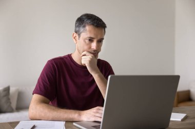 Orta yaşlı bir adam masasında oturur, düşünceli bir şekilde kendisine gelen e-postayı ya da mesajı inceler, düşünceli bir ifadeyle dizüstü bilgisayarda çalışır, yeni bir platform öğrenir, derinlemesine yoğunlaşır, sorunu çözer, verileri analiz eder.