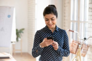 Yaratıcı iş yerinde akıllı telefon kullanan Hintli kadın müşterilerle iletişim kuruyor, programları veya işle ilgili görevleri yönetiyor, iş arkadaşlarıyla bağlantıda kalıyor, yeni mobil uygulamalar indiriyor