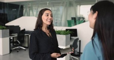 Orta Doğulu başarılı genç iş kadını Asyalı bayan meslektaşıyla el sıkışıyor, mülakat üstüne iş adayı kiralıyor, uzlaşma sağlıyor, profesyonel destek için teşekkür ediyor.