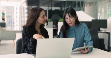 Proje için yaratıcı fikirler üzerinde birlikte çalışan, bir dizüstü bilgisayarı paylaşan, konuşan ve daktilo kullanan, etkin takım çalışması yaklaşımını kullanan olumlu, genç Asyalı ve Ortadoğulu kadın yöneticiler.