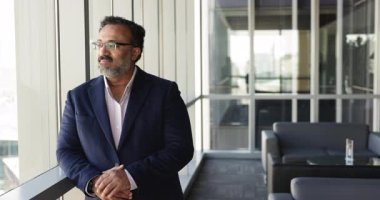 Olumlu, hayalperest, olgun Hintli şirket CEO 'su ofis salonundaki iş fikirlerini düşünüyor, büyük pencereden bakıyor, gülümsüyor, mutlu oluyor. Düşünceli Hintli kıdemli işadamı samimi bir portre
