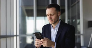 Resmi ceketli ciddi bir İspanyol şirket yöneticisi online işlemler, ödemeler, cep telefonunda daktilo yazma, başka yöne bakma, düşünme için akıllı telefondan finansal servisi kullanıyor.