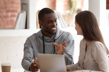 Motive olmuş Afro-Amerikan erkek öğrenci beyin fırtınası kadın takım arkadaşıyla fikirleri tartışır, akıllı odaklı çok ırklı milenyum eşleri laptop ve takım çalışması konseptini kullanarak çalışma hakkında konuşur.