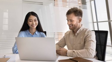 Verimli işbirliği. Gülümseyen dost canlısı iş ekibi iki farklı etnik çeşitlilikte ofis çalışanı iş yerinde bilgisayar kullanarak proje üzerinde çalışıyorlar başarılı fikirleri tartışıyorlar.