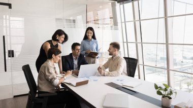 Etkili proje yönetimi. Değişik yaşlardaki iş adamlarından oluşan yaratıcı çok kültürlü bir grup olgun erkek CEO 'nun liderliğindeki takım arkadaşları yeni bir çözüm geliştirmek için dizüstü bilgisayar kullanıyorlar.