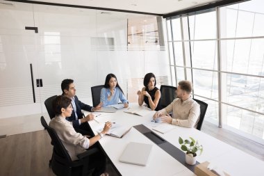 Yaratıcı beyin fırtınası. Çeşitli çok kültürlü yöneticiler, yöneticiler girişimciler grubu, iş geliştirme konusunda işbirliği yapmak için modern kurumsal ofiste masanın etrafında toplanıyor.