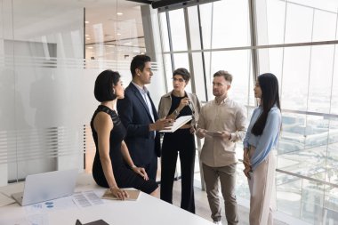 İş yerinde akıl hocalığı. Odaklanmış iş arkadaşları iş arkadaşları stajyerler ofiste olgun erkek lider uzman danışman etrafında durup profesyonel sözleşme detaylarını dinliyorlar.