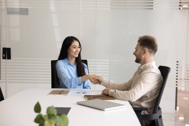 Anlaşmaya varılıyor. Muhtelif cinsiyet kökenli iki bin yıllık iş ortakları ofis masasında el sıkışırken, işbirliği yaparak yapılan başarılı pazarlıklar sonrasında güven gösteriyorlar.