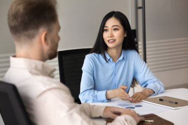 İş yerindeki veri analizi. Genç Asyalı iş kadını ofis çalışanı iş belgelerini tartışıyor istatistiksel bilgi gözden geçirme kriterleri raporunu sunuyor ve erkek lider meslektaşından geri bildirim alıyor