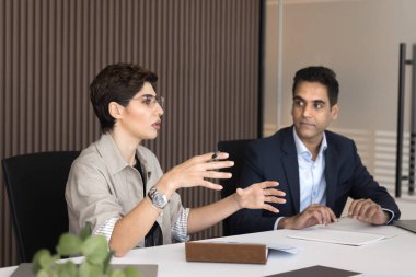 Stratejik vizyon paylaşımı. Ciddi stil sahibi gündelik kıyafet giymiş bir iş kadını ortaklarla görüşmeler hakkında konuşur toplantı odasında beyin fırtınası hakkında fikir beyan eder hissedarları projeye yatırım yapmaya ikna eder