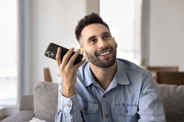 Elinde akıllı telefon dinleyen güler yüzlü bir adam neşeli yüzlü bir sesli mesaj ya da sesli mesaj almış, hoş bilgiler almış, iyi haberler almış, sohbetin keyfini çıkarmış, arkadaş ya da aileyle uzaktan iletişim kurmuş. Teknoloji