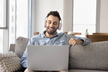 Adam kulaklık takıyor, film izliyor veya içeriği yayınlıyor, çevrimiçi kursa veya özel derse katılıyor, arkadaşıyla video görüşmesine katılıyor, hobiden hoşlanıyor, video düzenliyor, müzik yapıyor, dizüstü bilgisayar kullanarak dizayn ediyor.