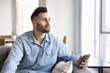 Genç İspanyol bir adam rahat bir koltukta oturur, akıllı telefonu tutar, düşünceli bir şekilde uzaktan bakar, derin bir düşünce ya da beklenti içinde, mesaj bekler, arar ya da gelen bilgiyi düşünür.