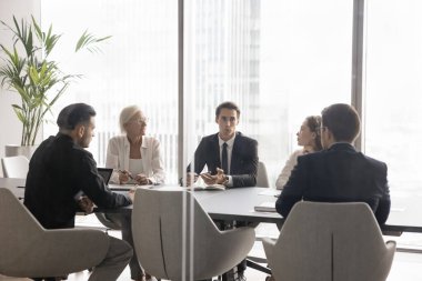 Liderlik ve takım çalışması. Modern etkin genç şirket lideri, proje ilerlemesi hakkında brifing vermek için ofis yönetim kurulu masasında çeşitli yöneticileri toplayıp takım vizyon değerleri hakkında konuşun.