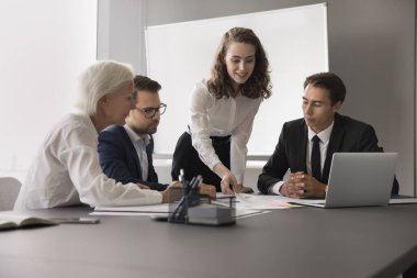 İnşaat ekibi sinerjisi. Gülümseyen genç kız koç çeşitli yaş grupları için antrenörlük yapıyor şirket yöneticileri kağıt döküman dağıtıyor grup çalışmalarında başlangıç görevi hakkında bilgi okumayı öneriyorlar