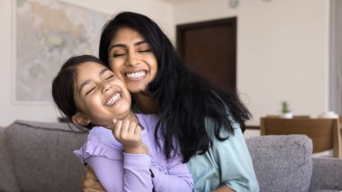 Sevgi dolu anne, sevimli beşli kızına sıkıca sarılıyor. Anaokulu kızı, evde, kanepede oturan genç ve güzel annesiyle oyun ve hassas anların tadını çıkarır. Sevgiyi hisseder, sevgisini ifade eder.