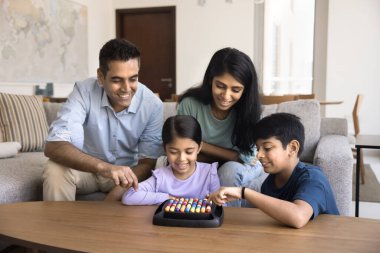 İki çocuk hafta sonları aileleriyle evde oyun oynuyorlar. Ebeveynler, çocukların gelişimini, becerilerini ve yaratıcılığını geliştirme ve problem çözme becerilerini geliştirme amaçlı eğitim oyunlarından hoşlanırlar