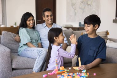 Ebeveynler kanepede oturur, iki çocuk birlikte oynar, beşlik çakar, renkli yapı taşlarıyla başlar ya da bitirirler, başarılı takım çalışmalarını kutlarlar. Aile bağı, yaratıcılık ve birliktelik.