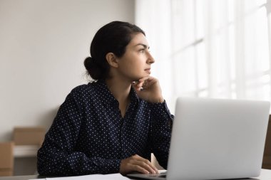 İş görüşü. Düşünceli genç bayan çevrimiçi ekommerce web mağazası yöneticisi depo ofisinde defter başında oturmuş teslimat lojistiği üzerinde kafa yoruyor başarılı satışlar için pazarlama stratejisi yaratıyor.