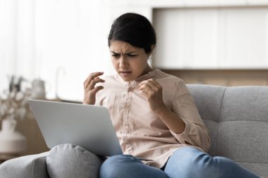 Bilgisayarda sorun var. Sinirli genç kız dizüstü bilgisayarla kanepede oturuyor öfke endişesi yavaş internet sinyalleri zayıf kablosuz bağlantı başarısız oldu e-posta iletilerinde dolandırıcılık spam alınıyor