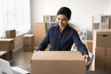 Paketle ve teslim et. Mutlu genç kadın tüketici malları tedarikçisi müdür teslimat servis işçisi depo çalışanı müşteri siparişlerini büyük karton kutuda paketliyor tüketici mallarını posta taşımacılığı için hazırlayın