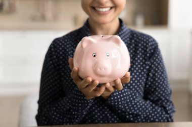 Finansal okuryazarlık. Kapalı kapılar ardında mutlu genç bir kadın oyuncak kumbarasını elinde tutuyor. Ülke ekonomisi, gelecekteki güvenilir banka mevduat yatırımı sermaye birikimi konsepti için tasarruf ediyor