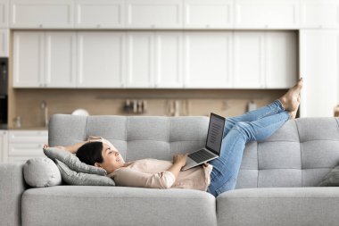 Kanepede çalışıyorum. Mutlu gülümseyen genç bayan serbest yazar blogcusu evde dizüstü bilgisayarla yaratıcı çalışmanın keyfini çıkarıyor.