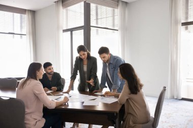 Verileri analiz eden beş profesyonel, konferans masasında hazırlanmış kağıtları gözden geçiriyorlar. İş projesi, strateji geliştirme veya sorun çözme konularında detaylı analizler yapan ekip, stratejik planlar yapar.