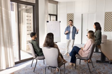 Genç Arap işletme koçu flip chart sunumu yapıyor, fikir sunuyor, hedefleri karşılıyor, proje güncellemelerini gözden geçiriyor, yaklaşan görevleri ve stratejileri planlıyor