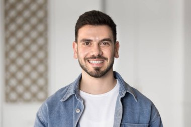 25 'li yaşlarda genç bir Orta Doğulu ofiste ya da yurtiçi alanda tek başına dikilirken kameraya bakıyor, kendinden emin görünüyor ve tatmin oluyor. Şirket çalışanı, serbest çalışan birinin portresi. Kariyer