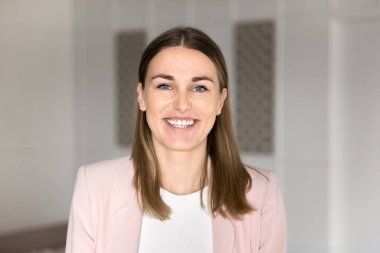 Resmi giyinmiş Avrupalı bir iş kadınının, çalışma alanında kameraya bakarken yakın plan fotoğrafı. Yönetici müdürü, şirket patronu veya şirket çalışanlarının profil fotoğrafı