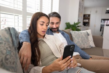 İnternet hizmetini kullanan çift, internet iletişimi için akıllı telefon uygulaması, alışveriş, online sipariş, rezervasyon, evdeki kanepede dinlenme. Karı koca cep telefonuyla sosyal medyayı kucaklıyor..