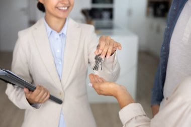 Mutlu Hintli emlakçı kadın konaklama yerinden yeni ev sahiplerine, kiracılara, emlak anlaşmasını sonuçlandıran emlakçıya anahtar veriyor, gülümsüyor. Ev, daire satın alan bir çift. Eller yukarı.