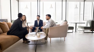 Geniş bir çalışma alanında dört çoklu etnik takım arkadaşı beyin fırtınası fikirleri, brifinge katılırlar, düşüncelerini, vizyonunu ve bilgilerini paylaşırlar, verimli bir toplantıda yer alırlar, ofiste takım çalışması yaparlar.