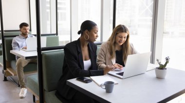 Modern çalışma odasındaki farklı insanların çalışma günü, takım çalışmasına katılan iki bayan meslektaşı, rahat bir masada oturan dizüstü bilgisayarda tele-iş yapan genç adam. İnternet kullanarak verimli iş akışı