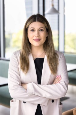 Milenyum işkadını zarif bir ceket giymiş modern bir iş arkadaşı gibi duruyor, kollarını kavuşturup kameraya bakıyor. Profesyonellik, yeterlilik, güvenilir şirket temsili portresi