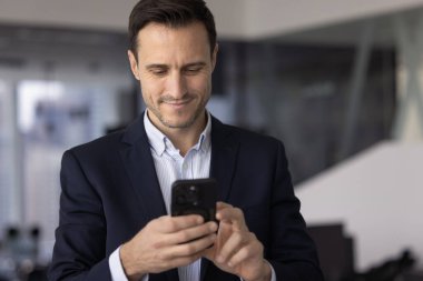 Ofiste akıllı telefonda yazan, gülümseyen, modern teknolojiyi kullanan, çevrimiçi finans uygulaması, internet iletişimi için dijital aygıt üzerindeki web servisi,