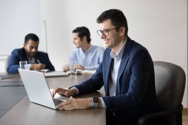Takım elbise giymiş, üretken, laptopa odaklanmış, raporları inceleyen ya da hazırlayan, çevrimiçi sunum yapan, verileri analiz eden, görevleri koordine eden olgun bir işadamı. Strateji planlaması
