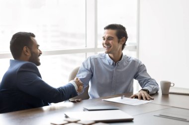 İki çok uluslu işadamı, profesyonel ortaklık kurarak el sıkışıyor ve müzakerelerin başarıyla tamamlanmasıyla birbirlerini tebrik ediyorlar. Karşılıklı memnuniyet ve saygı jesti, güven