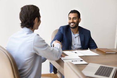İki çok ırklı profesyonel anlaşma imzalarken, konferans masasında oturup karşılıklı saygı, işbirliği ve başarılı ortaklık veya anlaşmaya ortak olma vaatlerini dile getiriyorlar.